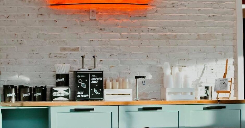 Stylish dining area featuring contemporary furniture and a vibrant neon sign saying 'Out of Your League.'